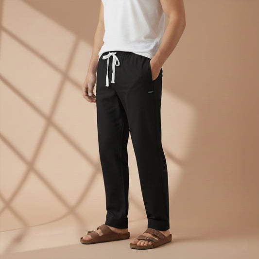 Person wearing black pants with a white drawstring, standing against a beige background