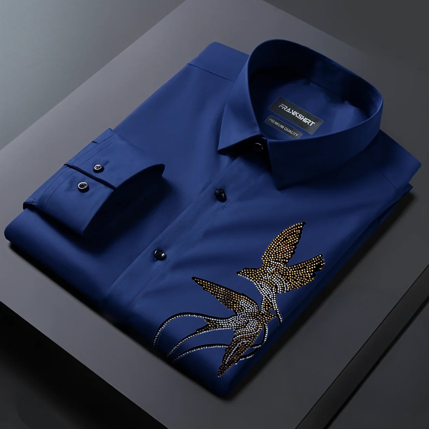 Folded blue shirt with a decorative emblem on a dark surface