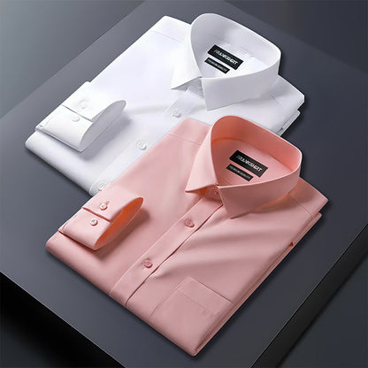 Two folded dress shirts, one white and one pink, on a dark surface with a brand label visible.